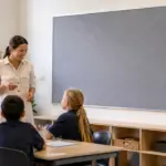 Teacher and students beside a large grey classroom pinboard